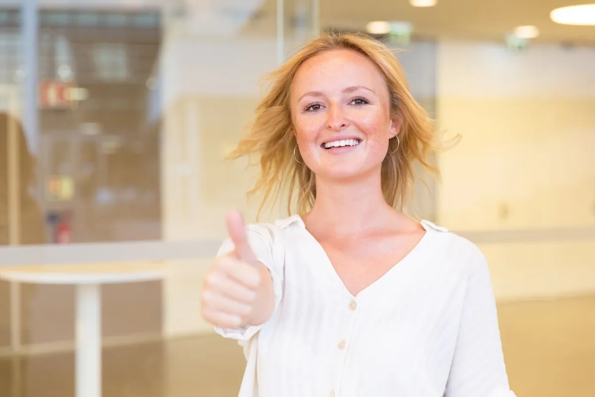 a smiling woman doing a thumbs-up
