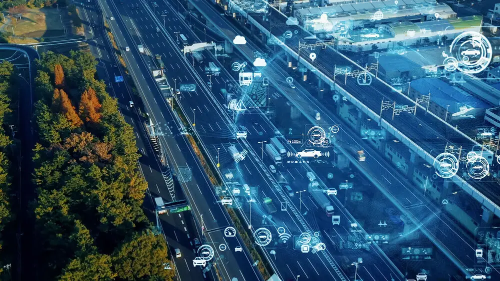 An aerial view of a busy highway running alongside an industrial area and forest