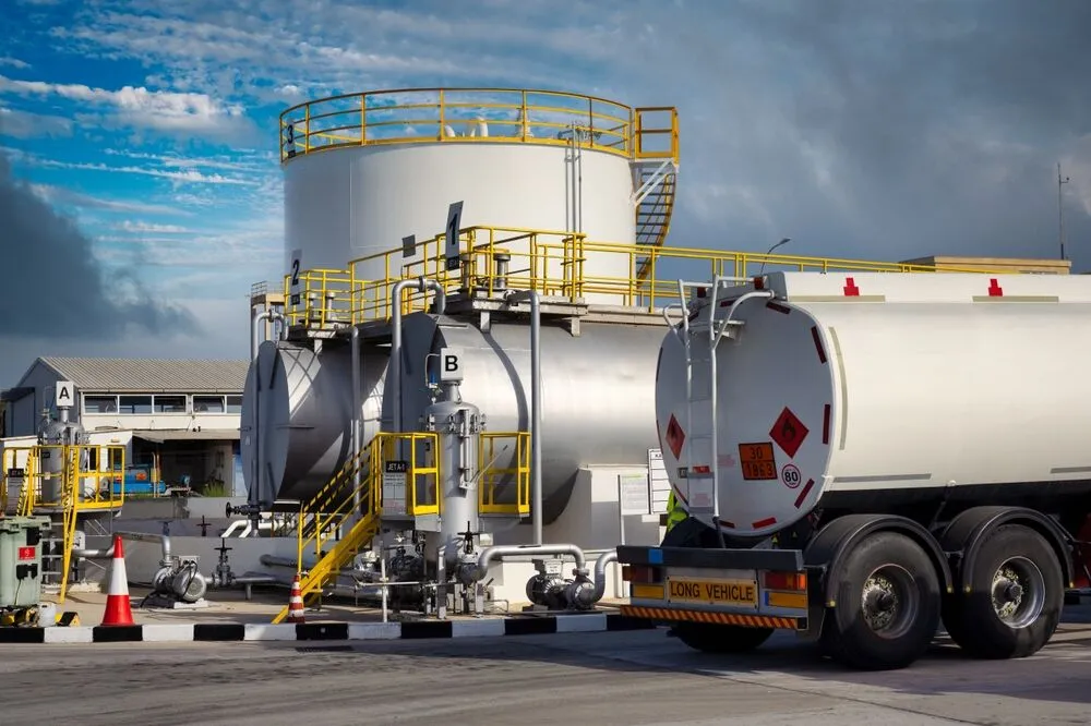 A white fuel tanker truck parked at an industrial terminal