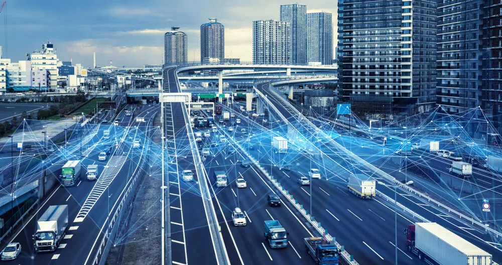 An elevated view of a busy multi-lane city highway filled with trucks and cars.