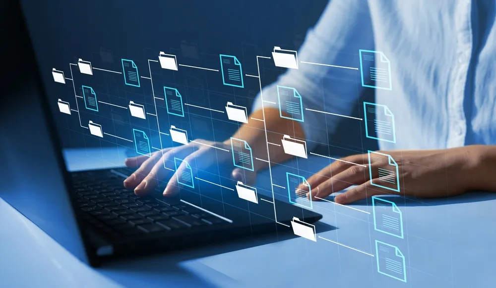 Hands typing on a laptop, with a diagram of linked folders and files drawn above the keys