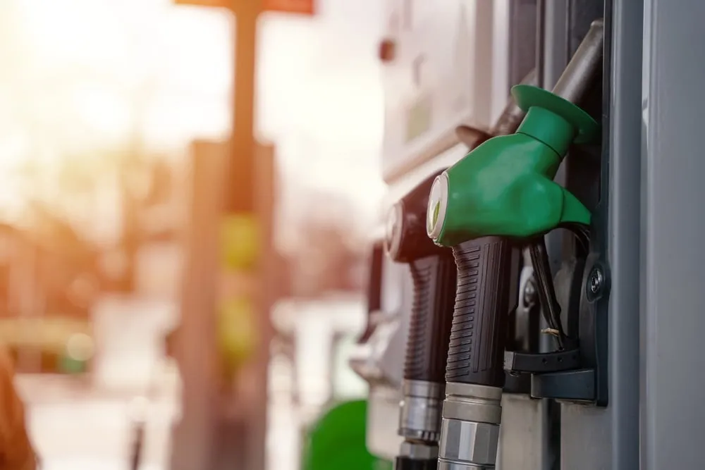 A close-up of a green fuel nozzle resting in its holster at a gas pump